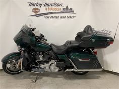 a green and black motorcycle is parked in a room with a sign on the wall