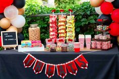 a table topped with lots of candy and snacks next to balloons in the shape of letters