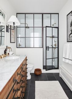 a bathroom with black and white tile flooring next to a walk in shower stall