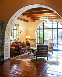 a living room filled with lots of furniture next to an arched doorway that leads into a patio