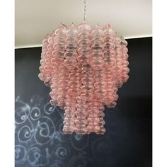 a pink chandelier hanging from a ceiling in a room with black wallpaper