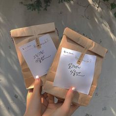 two brown paper bags with writing on them and someone holding one in the other's hand