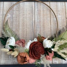 a wreath with flowers and feathers is hanging on a wall