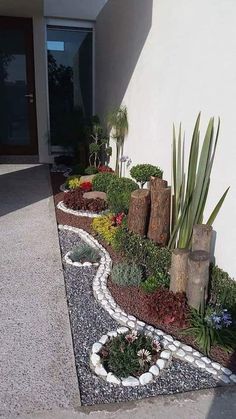 a garden with rocks and plants in front of a house