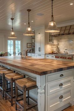 a large kitchen island with stools next to it and lights hanging from the ceiling