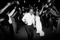 a man and woman are holding sparklers as they walk down the street with their arms in the air