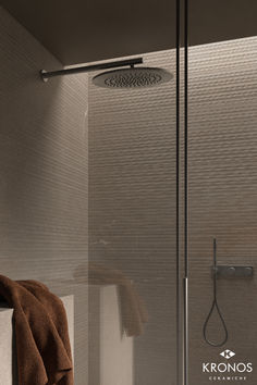 a bathroom with a glass shower door and brown towels on the towel rack next to it