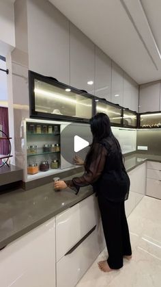 a woman standing at the counter in a kitchen