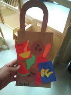 someone is holding up a paper bag with cut outs on it that have fruit and vegetables in them