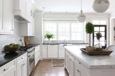 a kitchen with white cabinets and black counter tops, along with a bowl of fruit on the island