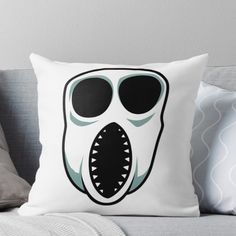 a pillow with a shark's mouth and teeth on the front, sitting on a couch