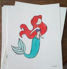 two sheets of paper with drawings of a mermaid and a fish on them, sitting next to each other