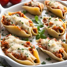 several stuffed shells with meat and sauce in a white casserole dish, garnished with parsley