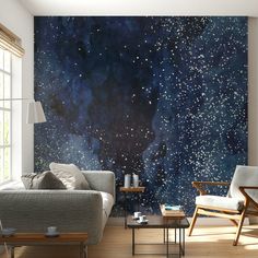 a living room filled with furniture next to a wall covered in stars and space paint