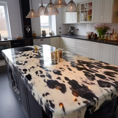 a kitchen with an island made out of cow hides and lights hanging from the ceiling