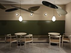 three chairs and two tables in a room with green paneling on the wall behind them