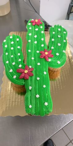 a cake shaped like a cactus sitting on top of a table next to a cupcake