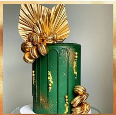 there is a green cake with gold decorations on the top and bottom, decorated with golden ribbons