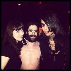 three women and one man are posing for a photo together in the dark with their shirt off