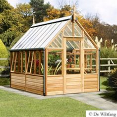 a small wooden greenhouse sitting on top of a lush green field