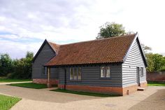 a small gray house with a red roof and brown shingles on the top floor