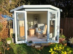 a small white shed sitting on top of a lush green field