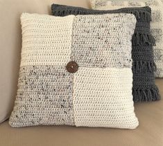 three crocheted pillows on a couch with buttons in the middle and one button at the back