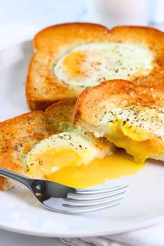 two pieces of toast with an egg in the middle on a plate next to a fork