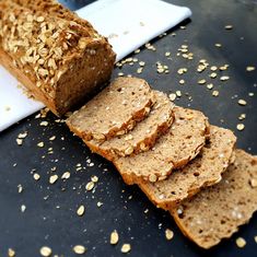 a loaf of bread sitting on top of a cutting board next to sliced oats