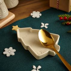 a gold spoon sitting on top of a white dish next to snowflakes and christmas decorations