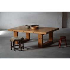 a wooden table with two stools and a bowl sitting on top of the table