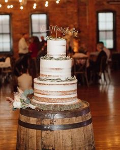 a wedding cake sitting on top of a wooden barrel