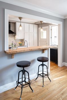 two stools are in front of the kitchen counter and bar with an oven on it