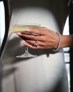 a woman's hand holding a wine glass with a diamond ring on the finger