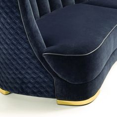 a blue velvet couch with gold trimmings on the arm and back, sitting in front of a white background