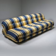 a blue and yellow striped couch sitting on top of a white floor next to a wall