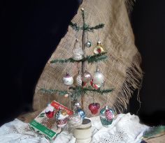 a small christmas tree with ornaments in it on a doily cloth covered tablecloth