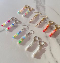 six pairs of beaded earrings on a marble surface