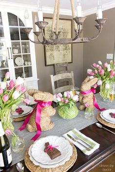 a dining room table set for easter with bunny decorations and flowers in vases on it