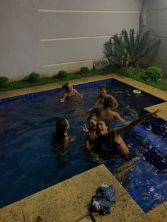 several people in a swimming pool playing with a frisbee and water hoses