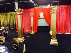 an elaborately decorated event with red and gold drapes, black carpet, and chairs