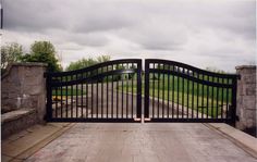 an iron gate is opened to allow people to walk into the park on a cloudy day