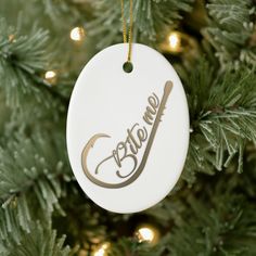 a white ornament hanging from a christmas tree with the word give me written on it