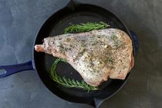 a piece of meat sitting on top of a frying pan filled with green herbs