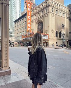 a woman standing on the sidewalk in front of a theater