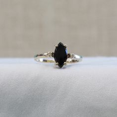 This ring is a unique combination of a marquise shaped black onyx and yellow gold. Two tiny accent diamonds add .01 carats of sparkle. Prong set stones Black Marquise Diamond Rings, Black Marquise Ring Gift, Black Marquise Ring As Gift, Black Marquise Diamond Jewelry, Black Marquise Ring For Gift, Black Marquise Cut Gemstone Ring, Black Marquise Cut Promise Ring, Elegant Ring With Diamond Eyes For Anniversary, Elegant Rings With Diamond Eyes For Anniversary