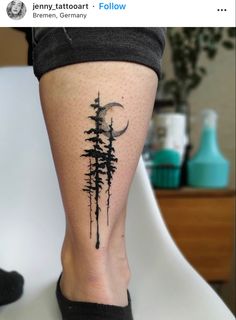 a person with a tattoo on their leg that has trees and a moon in the background