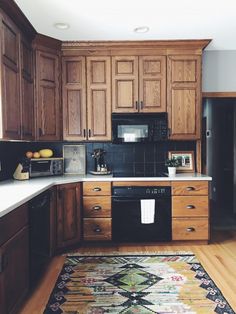 a kitchen with wooden cabinets and an area rug in front of the stove top oven