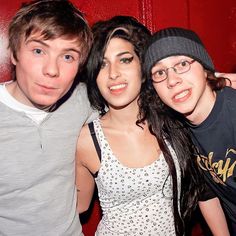 three people posing for a photo in front of a red wall