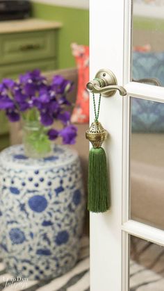 a vase with purple flowers and a green tassel hanging from it's side